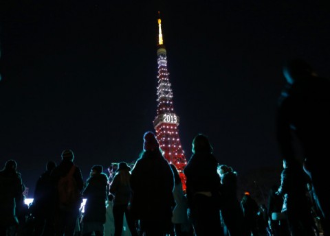 People look at the Tokyo Tower which is illuminated to celebrate the New Year at a countdown event in Tokyo